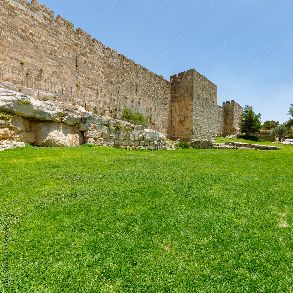 Grass lawn and ancient wall of old city Jerusalem