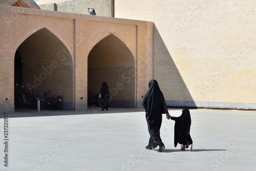 Muslim mother with the daughter with traditional chador is going along streets in Isfahan city, Iran photo