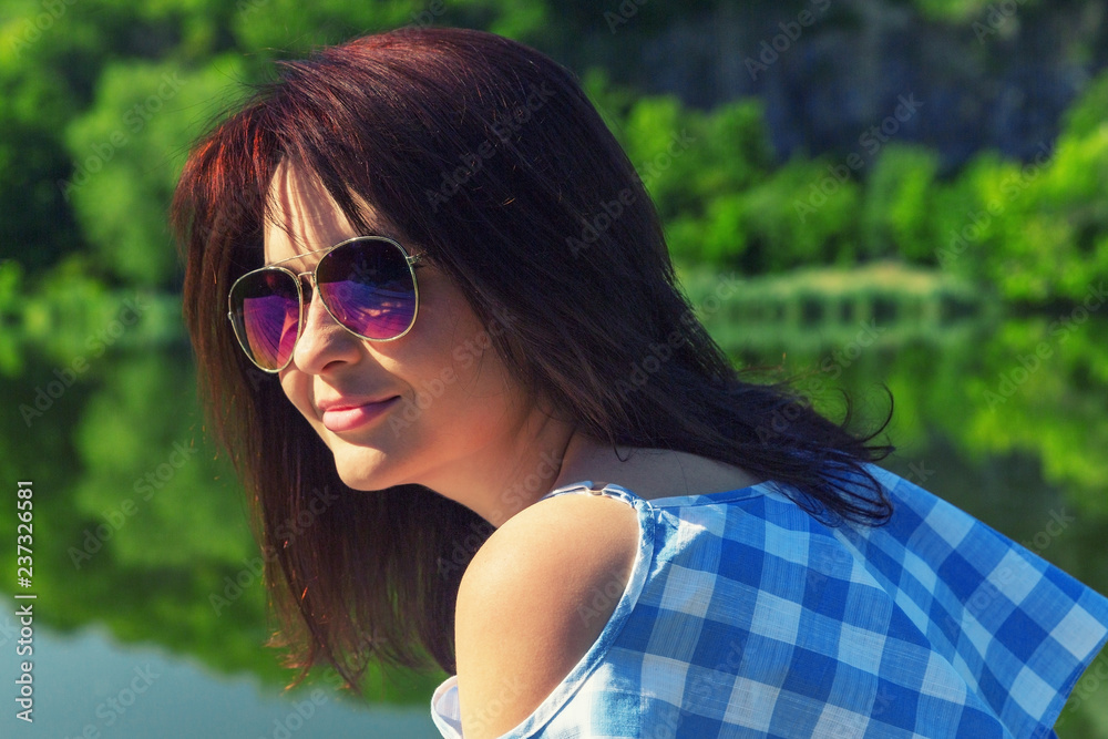 Young woman in sunglasses sits on the bridge near the river on a sunny day. Young woman in sunglasses sits on the bridge near the river on a sunny day.
