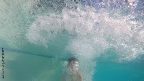 Underwater slow motion of young boy doing a cannonball into pool