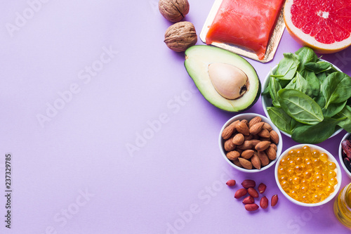 Concept Healthy food antioxidant products: fish and avocado, nuts and fish oil, grapefruit on pink background. Copy space
