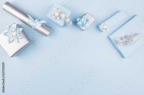 Elegance blue festive gift boxes with silver ribbons, bows and snowflakes as border on white wood table, top view, copy space.