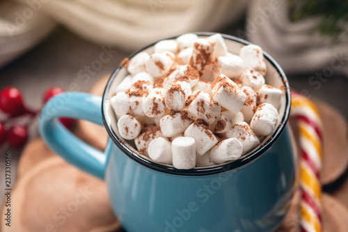 Mug of hot chocolate with marshmallow and a Lollipop stick on a knitted blanket background. Cozy warm winter composition