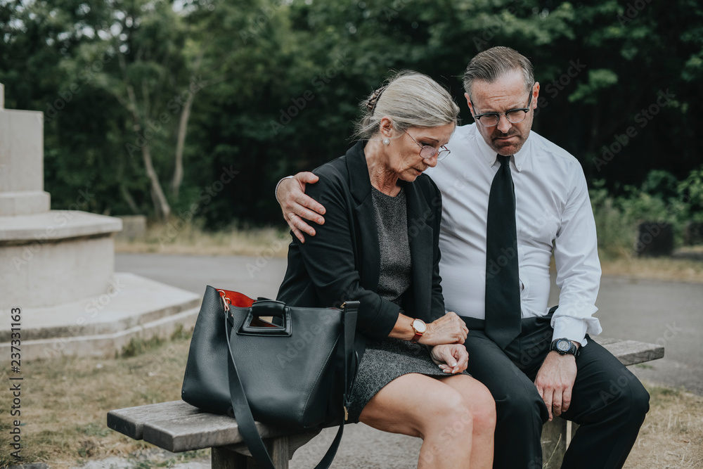 Couple grieving their loss at a cemetery Couple grieving their loss at a cemetery