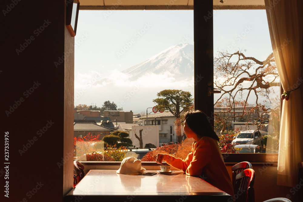 Young asian woman admire view of fuji mountain by window in hotel have coffee in m orning