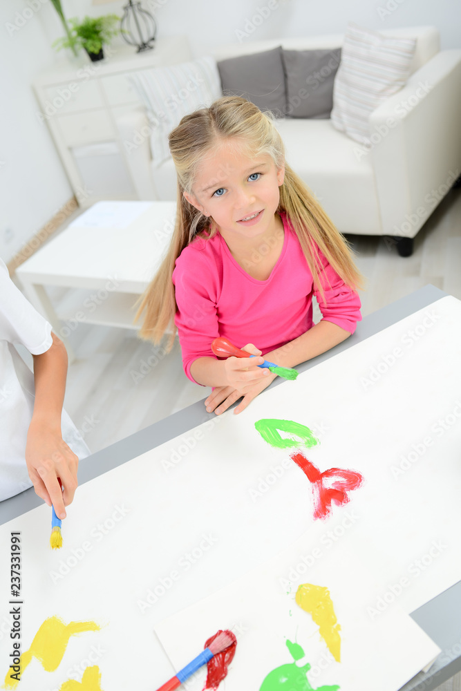 portrait of a beautiful young kid girl painting on a white paper with color paint at home portrait of a beautiful young kid girl painting on a white paper with color paint at home