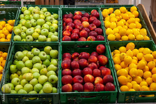 A large rack with baskets with different types of apples and lemons in the fruit department of the shopping center. Fresh and healthy foods for every day diet.