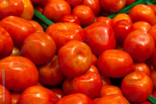 Close-up on a large number of tomatoes brightly red from fresh harvest ready for sale lying on the counter in the vegetable department of the shopping center
