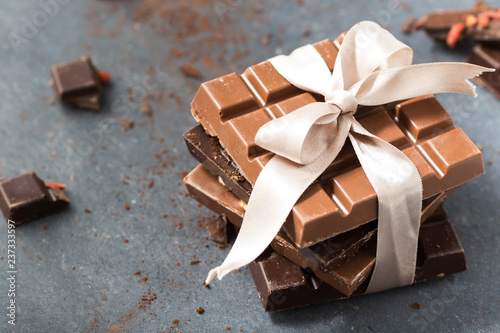 Chocolate bars with white bow on a grey background