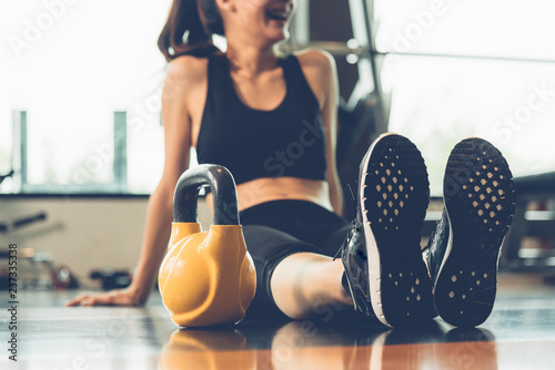 Relaxing, happy woman sitting with dumbbells after workout