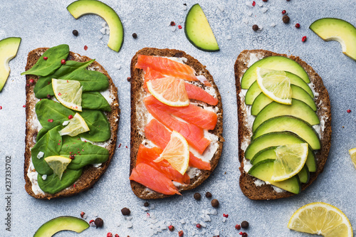 Open sandwiches with spinach and avocado salmon on a grey table. photo