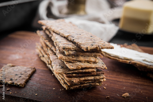 Photos Useful rye crispbread on a wooden board against a dark background