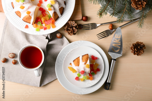 Plates with delicious Christmas cake and cup of tea on wooden table