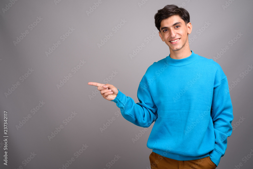 Young happy Persian teenage boy smiling and showing copyspace Young happy Persian teenage boy smiling and showing copyspace