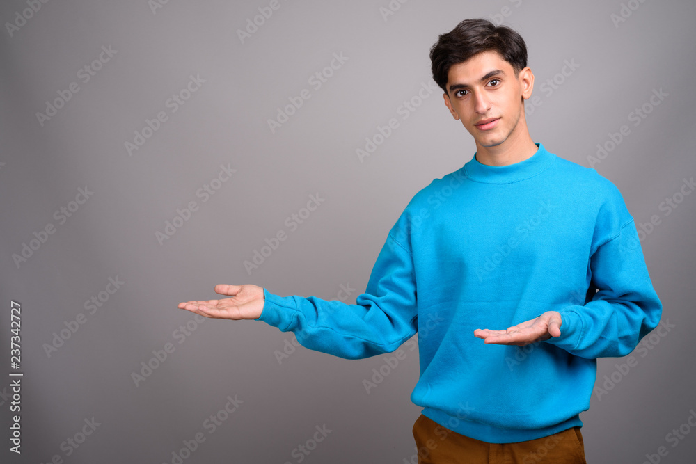 Young handsome Persian teenage boy showing copyspace Young handsome Persian teenage boy showing copyspace