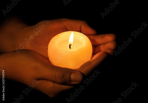 Woman holding burning candle on dark background