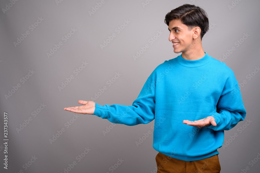 Young handsome Persian teenage boy showing copyspace Young handsome Persian teenage boy showing copyspace