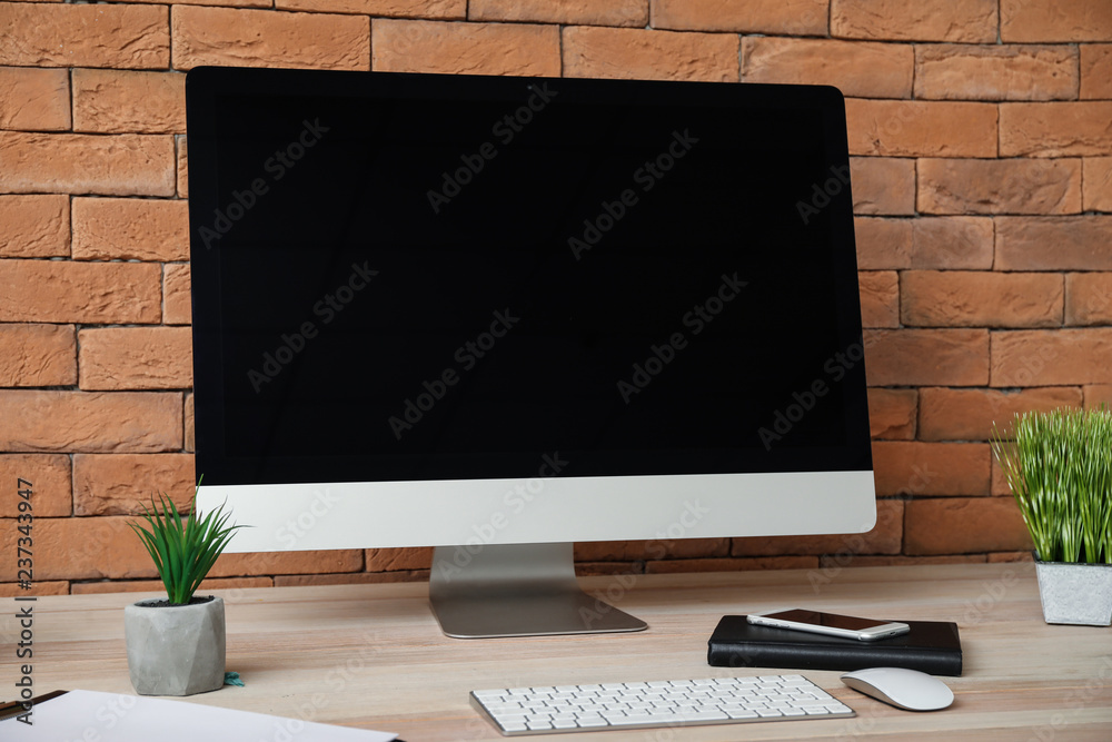 Fototapeta premium Stylish workplace with modern computer near brick wall
