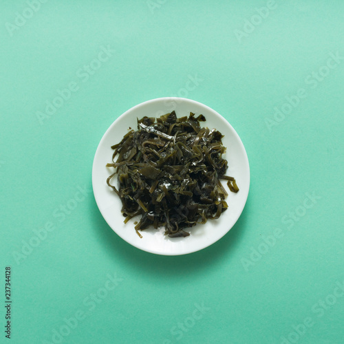 Seaweed food salad on green background, top view, flat lay