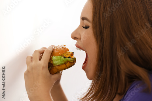 Young woman eating tasty burger  closeup