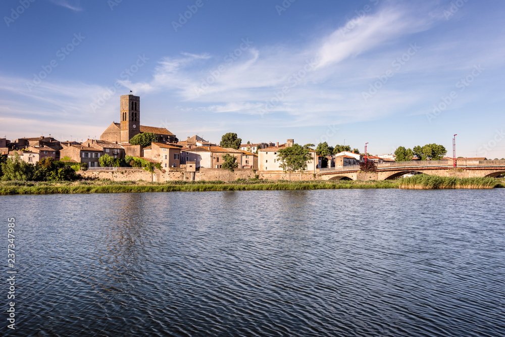 France, Trebes, near Carcassonne: Panorama skyline view of French small town with Aude river, Church Saint Etienne, cityscape, skyline bridge and blue sky in the background - concept travel history