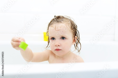 Little girl taking bath and playing toys