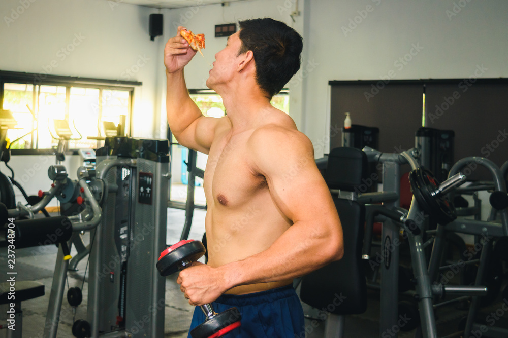 Asian man has muscle Eating pizza and lifting dumbbell Asian man has muscle Eating pizza and lifting dumbbell