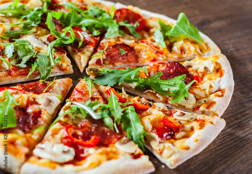 Pizza with Mozzarella cheese, mushrooms, pepperoni, tomato sauce, salami, pepper, Spices and Fresh arugula. Italian pizza on wooden table background Pizza with Mozzarella cheese, mushrooms, pepperoni, tomato sauce, salami, pepper, Spices and Fresh arugula. Italian pizza on wooden table background