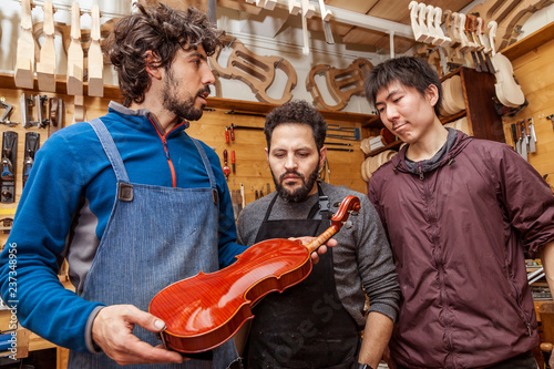 group of craftsmen violinmakers testing a new violin
