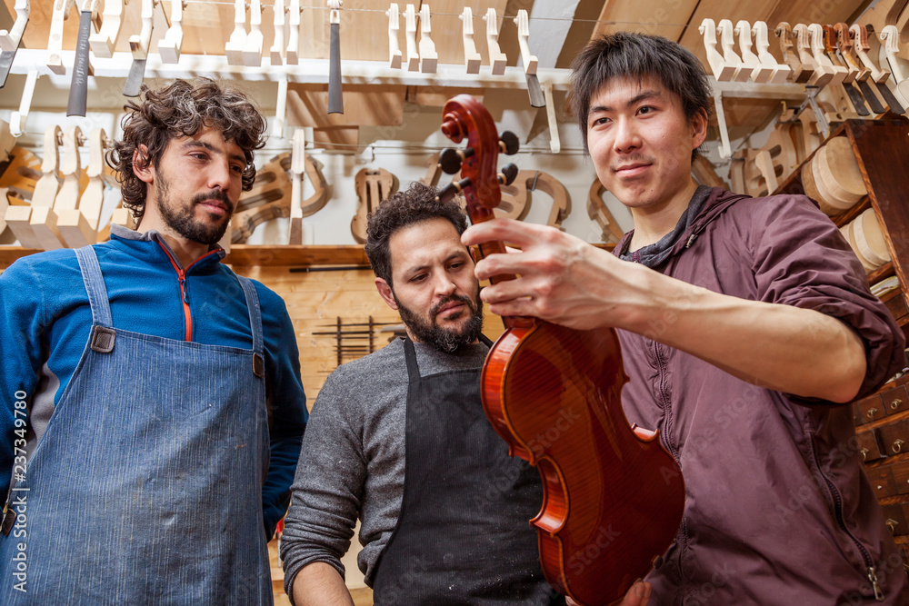 group of craftsmen violinmakers testing a new violin