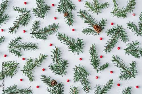 Fir branches with red berries background pattern. Winter flat lay composition. Top view.