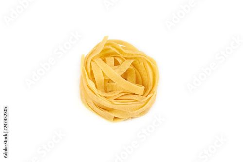 Uncooked nest of tagliatelle pasta isolated on white background.