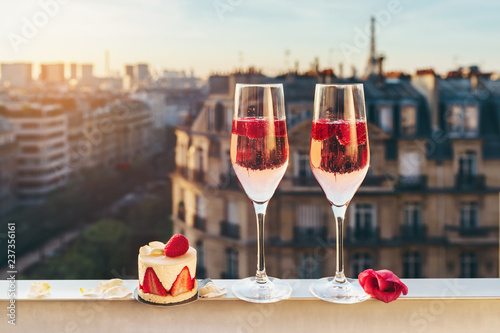 Paris luxury lifestyle. Pink champagne in two glasses, traditional french cake with strawberries on a balcony on the sunset © tiana__lima__