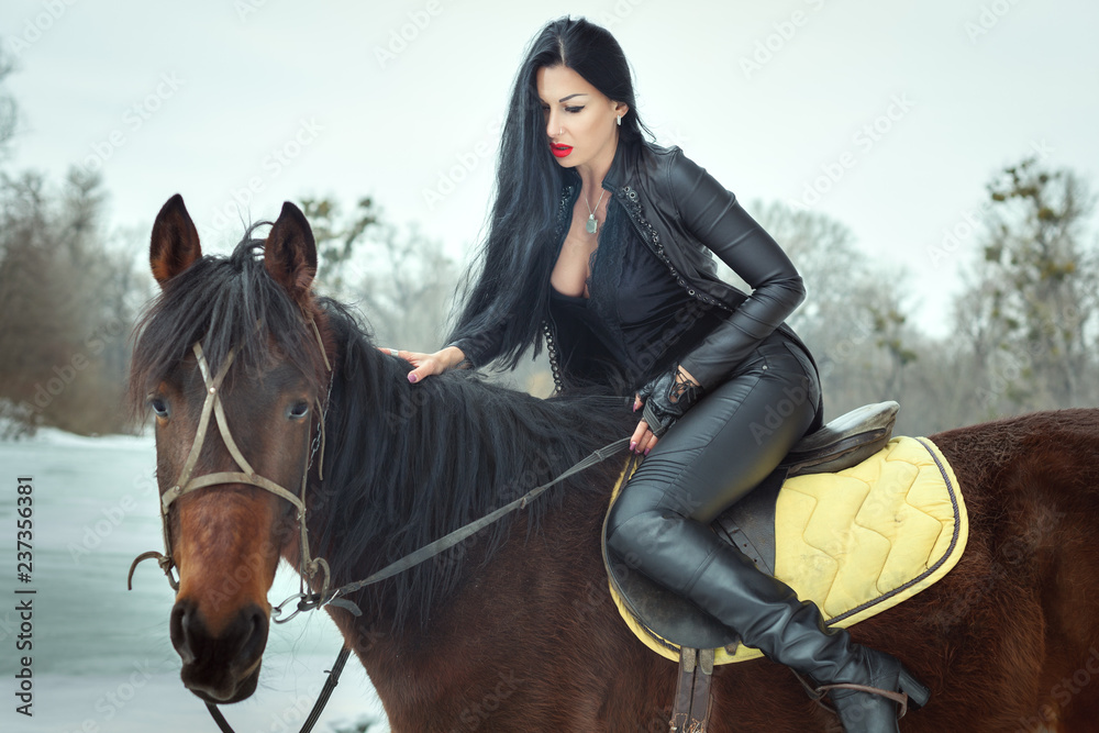 Obraz premium Beautiful brunette woman sitting on horseback.
