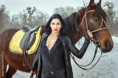 Foto Beautiful woman in a black suit near a horse.