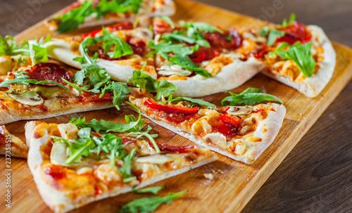 slices Pizza with Mozzarella cheese, mushrooms, pepperoni, tomato sauce, salami, pepper, Spices and Fresh arugula. Italian pizza on wooden table background