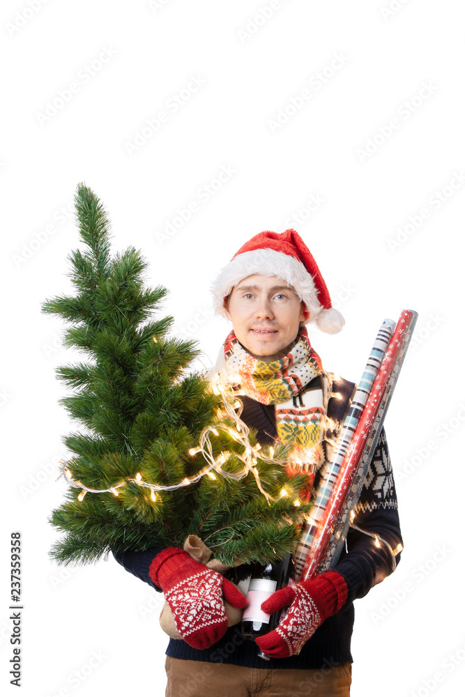 Photo of cheerful man in Santa's cap with Christmas tree with garland, wrapping paper in hands Photo of cheerful man in Santa's cap with Christmas tree with garland, wrapping paper in hands