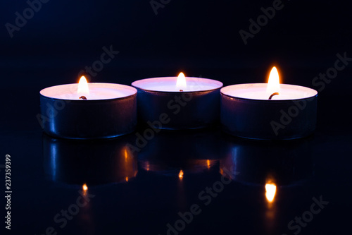 three candles in the dark with reflection
