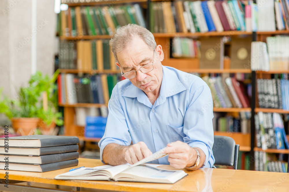 senior man reading a book in the library senior man reading a book in the library