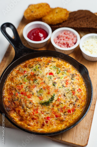 Frittata on a skillet with sauces and bread