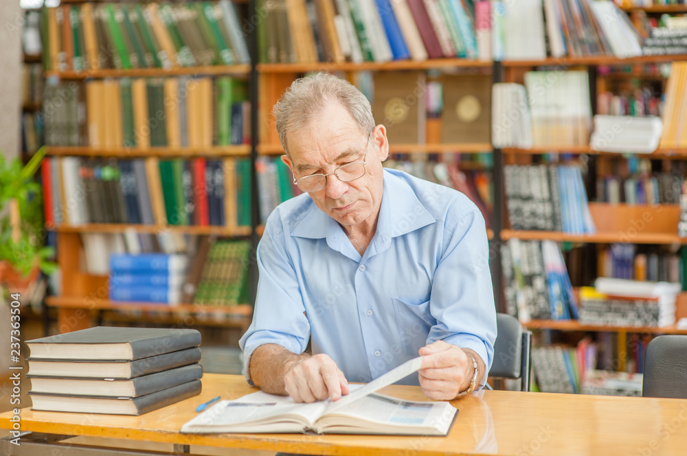 senior man reading a book in the library senior man reading a book in the library