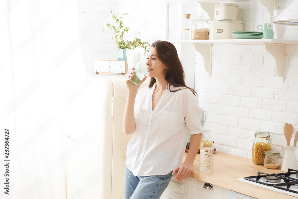 Young happy woman drinking coffee on the kitchen in the morning. Young happy woman drinking coffee on the kitchen in the morning.
