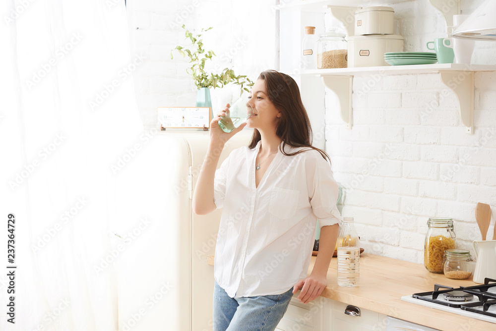 Young happy woman drinking coffee on the kitchen in the morning. Young happy woman drinking coffee on the kitchen in the morning.