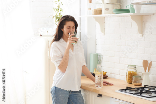 Young happy woman drinking coffee on the kitchen in the morning.