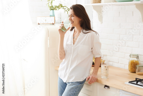 Young happy woman drinking coffee on the kitchen in the morning.