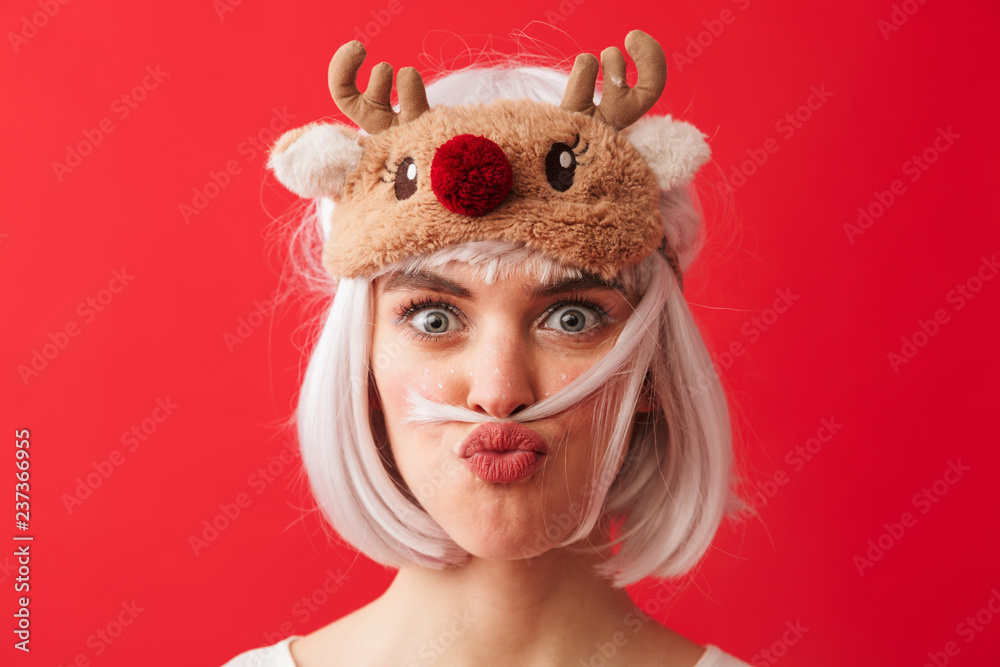 Funny woman dressed in carnival christmas costume posing isolated over red wall background having fun.