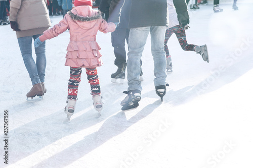 Father and daughter skate on the rink during the winter holidays. Joint pastime.