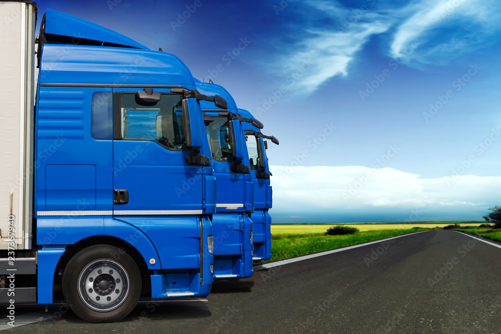 Three trucks in perspective along the road with blue sky on background