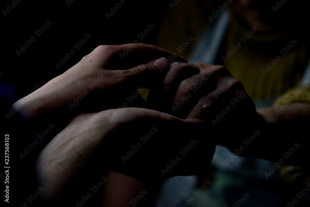 Young hands of daughter hold old hands of grandmother on dark background