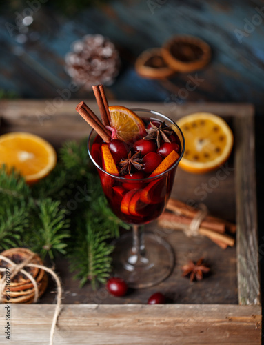 Christmas hot mulled wine in a glass with spices, citrus fruit and cranberry. Christmas atmosphere. 